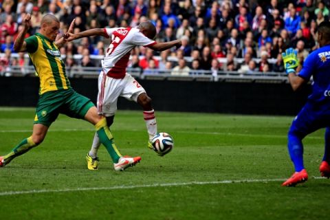 Ajax player Thulani Serero, center, scores the team's third goal passing ADO goalkeeper Gino Coutinho, right, and defender Vito Wormgoor, left, during the match between Ajax and ADO Den Haag at ArenA stadium in Amsterdam, Netherlands, Sunday, April 13, 2014. Ajax won with a 3-2 score, but did not clinch the Dutch title as nearest opponent Feyenoord also took 3 points with a win against PSV. (AP Photo/Peter Dejong)