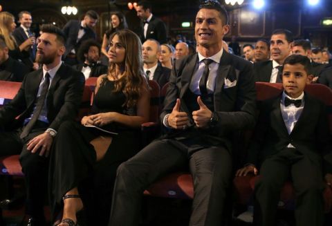 Portuguese soccer player Christiano Ronaldo, second from right, and son Cristiano Ronaldo Jr., right, sit beside Argentinian soccer player Lionel Messi, left, and wife Antonella during the The Best FIFA 2017 Awards at the Palladium Theatre in London, Monday, Oct. 23, 2017. (AP Photo/Alastair Grant)