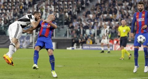 Juventus's Giorgio Chiellini, left, heads the ball past Barcelona's Javier Mascherano to score his side's third goal, during a Champions League, quarterfinal, first-leg soccer match between Juventus and Barcelona, at the Juventus Stadium in Turin, Italy, Tuesday, April 11, 2017. (AP Photo/Antonio Calanni)