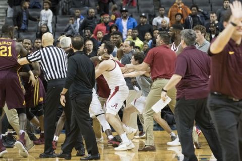 A member of the Minnesota caching staff, right, gestures for his players to stay on the bench after a fight during the second half of an NCAA college basketball game between Minnesota and Alabama, Saturday, Nov. 25, 2017, in New York. Minnesota won 89-84.(AP Photo/Mary Altaffer)