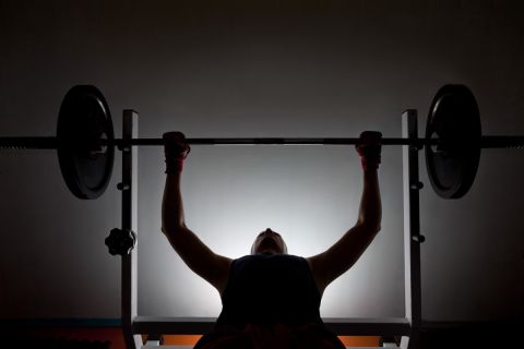 Man weightlifter at the gym, lifting weights on a benchpress