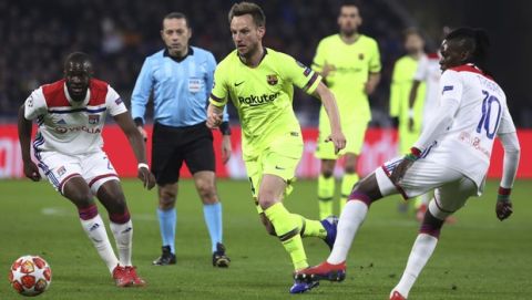 Lyon forward Bertrand Traore, right, and Lyon defender Mapou Yanga-Mbiwa, left, challenge Barcelona midfielder Ivan Rakitic, center, during the Champions League round of 16 first leg soccer match between Lyon and FC Barcelona in Decines, near Lyon, central France, Tuesday, Feb. 19, 2019. (AP Photo/Laurent Cipriani)