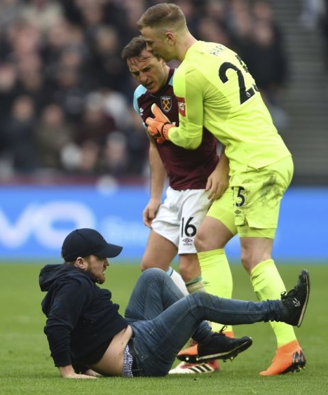 A Pitch invader falls to the pitch confronted by West Ham's Mark Noble, with goalkeeper Joe Hart, right, during the English Premier League soccer match between Burnley and West Ham at the Olympic London Stadium in London, Saturday, March 10, 2018. (Daniel Hambury/PA via AP)
