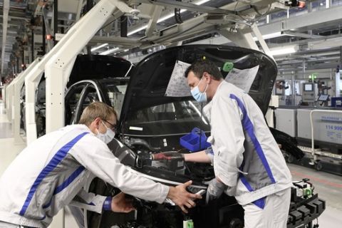 Two employees at Volkswagen in Zwickau install the headlight on the ID.3. For the restart of production, a catalogue of measures for health protection was agreed between the company and the works council, which provides for the wearing of mouth-nose protection at workplaces with a distance of less than 1. 5 metres from each other.
