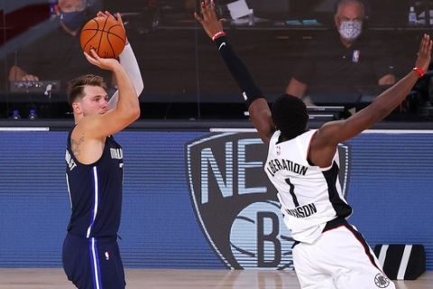 Dallas Mavericks' Luka Doncic, left, hits a winning three-point basket against Los Angeles Clippers' Reggie Jackson (1) during overtime of Game 4 of an NBA basketball first-round playoff series, Sunday, Aug. 23, 2020, in Lake Buena Vista, Fla. (Kevin C. Cox/Pool Photo via AP)