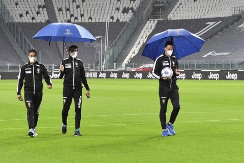 Referee Daniele Doveri, right, flanked by assistants Filippo Meli and Daniele Bindoni inspects the pitch of the Allianz Stadium in Turin, Italy, Sunday, Oct. 4, 2020 ahead of the scheduled Serie A soccer match between Juventus and Napoli. Napoli is likely to be handed a 3-0 loss by the Italian leagues judge for failing to show for its Serie A match at Juventus on Sunday night. Napoli did not travel to Turin for the match after local health authorities ordered the squad into quarantine after two players tested positive for the coronavirus. (Tano Pecoraro/LaPresse via AP)