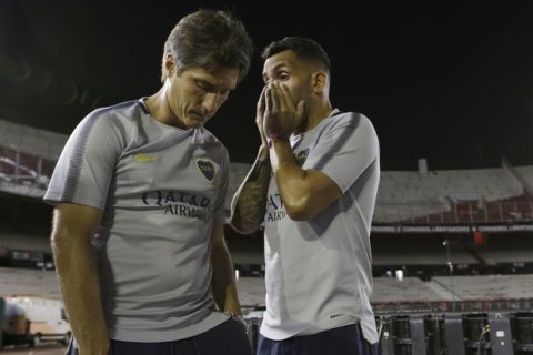 CORRECTS PHOTOGRAPHER"S BYLINE - Carlos Tevez of Argentina's Boca Juniors, talks with coach Guillermo Barros Schelotto in the Antonio Vespucio Liberti stadium after the Copa Libertadores championship match was rescheduled, in Buenos Aires, Argentina, Saturday, Nov. 24, 2018. The Saturday match was rescheduled for Sunday after the bus carrying the Boca Juniors players was attacked by River Plate fans, injuring several players including Perez. (AP Photo/Natacha Pisarenko)