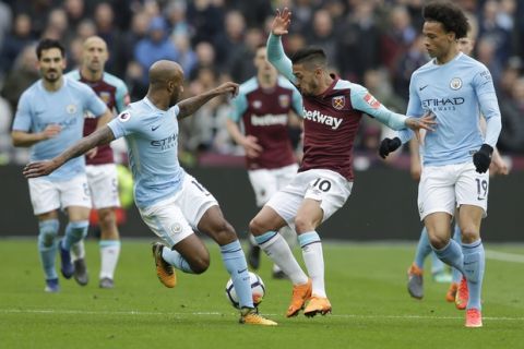 West Ham United's Manuel Lanzini , centre, attempts to control the ball from Manchester City's Fabian Delph, left, during the English Premier League soccer match between West Ham United and Manchester City at the London stadium in London, Sunday, April, 29, 2018. (AP Photo/Alastair Grant)