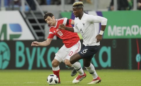 France's Paul Pogba, right, duels for the ball with Russia's Fyodor Smolov during the international friendly soccer match between Russia and France at the Saint Petersburg stadium in St.Petersburg, Russia, Tuesday, March 27, 2018. (AP Photo/Dmitri Lovetsky)