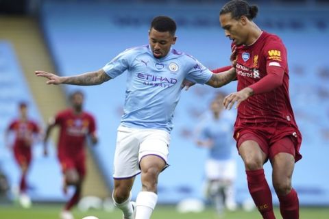Manchester City's Gabriel Jesus, left, and Liverpool's Virgil van Dijk battle for the ball during the English Premier League soccer match between Manchester City and Liverpool at Etihad Stadium in Manchester, England, Thursday, July 2, 2020. (AP Photo/Dave Thompson,Pool)