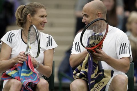 Former tennis champion Andre Agassi of the US, right, seen with to his wife, former tennis champion, German born Steffi Graf, left,  during a break in the mixed double tennis match against British tennis player Tim Henman and former tennis champion Kim Clijsters, from Belgian, during a test event on Wimbledon's Centre Court, in London, Sunday, May 17, 2009. Wimbledon's Centre Court has had a moveable roof installed so that play can continue at the grass court championships in wet weather. The Championships begin Monday June 22. (AP Photo/Alastair Grant)