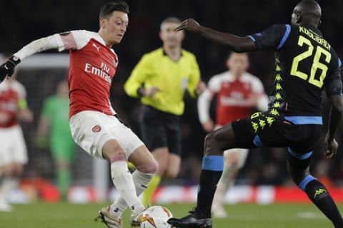 Arsenal's Mesut Ozil, left, challenges for the ball with Napoli's Kalidou Koulibaly during the Europa League first leg quarterfinal soccer match between Arsenal and Napoli at Emirates stadium in London, Thursday, April 11, 2019. (AP Photo/Kirsty Wigglesworth)
