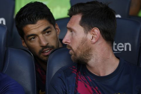 FILE - In this Sunday, Aug. 4, 2019 file photo, Barcelona's Lionel Messi, right, talks with teammate Luis Suarez on the bench before the Joan Gamper trophy soccer match against Arsenal at the Camp Nou stadium in Barcelona, Spain. Luis Suarez and Lionel Messi spent years hanging out at their neighboring homes on the Mediterranean coast when taking a break from scoring goals for Barcelona. On Saturday, May 8, 2021 Suarez will return to Camp Nou aiming to knock his former team out of the Spanish league title race.(AP Photo/Joan Monfort, file)