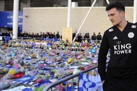 Leicester's Harry Maguire looks at tributes outside Leicester City Football Club after a helicopter crashed Saturday killing Leicester City's owner, Thai billionaire Vichai Srivaddhanaprabha and four other people, in Leicester, England, Monday Oct. 29 2018. The helicopter crashed in flames in a car park next to the soccer club's stadium shortly after it took off from the pitch following a Premier League game on Saturday night. (AP Photo/Rui Vieira)