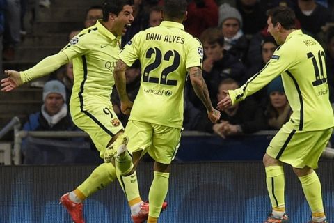 Barcelona's Uruguayan forward Luis Suarez (L) celebrates scoring the opening goal with Barcelona's Brazilian defender Dani Alves (C) and Barcelona's Argentinian forward Lionel Messi (R) during the UEFA Champions League round of 16 first leg football match between Manchester City and Barcelona at the Etihad Stadium in Manchester, northwest England, on February 24, 2015.  AFP PHOTO / LLUIS GENE        (Photo credit should read LLUIS GENE/AFP/Getty Images)