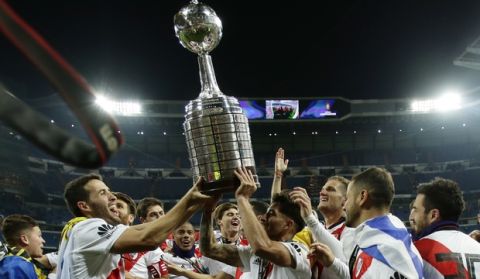 Payers of Argentina's River Plate celebrate with the trophy after defeating 3-1 Argentina's Boca Juniors in the Copa Libertadores final soccer match at the Santiago Bernabeu stadium in Madrid, Spain, Sunday, Dec. 9, 2018. (AP Photo/Manu Fernandez)