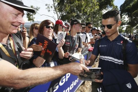 Sauber driver Pascal Wehrlein, right, of Germany signs autographs for fans on his arrival at the Albert Park track ahead of the first practice session for the Australian Grand Prix in Melbourne, Friday, March 24, 2017. (AP Photo/Rick Rycroft)
