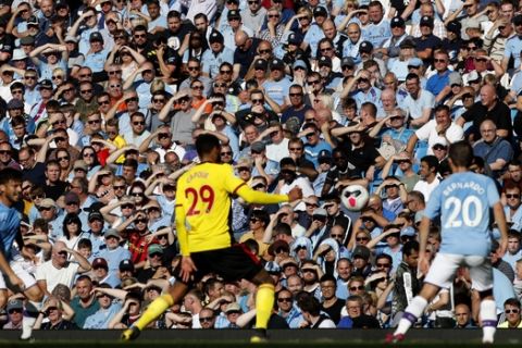 The crowd shields themselves against the sun during the English Premier League soccer match between Manchester City and Watford at Etihad stadium in Manchester, England, Saturday, Sept. 21, 2019. (AP Photo/Rui Vieira)