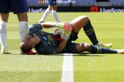 Arsenal's goalkeeper Bernd Leno grimaces on the ground after getting injured during the English Premier League soccer match between Brighton & Hove Albion and Arsenal at the AMEX Stadium in Brighton, England, Saturday, June 20, 2020. (Gareth Fuller/Pool via AP)