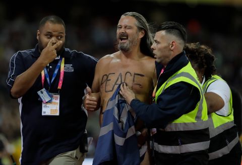 A streaker is apprehend by security after he ran on the track during the World Athletics Championships in London, Saturday, Aug. 5, 2017. (AP Photo/David J. Phillip)