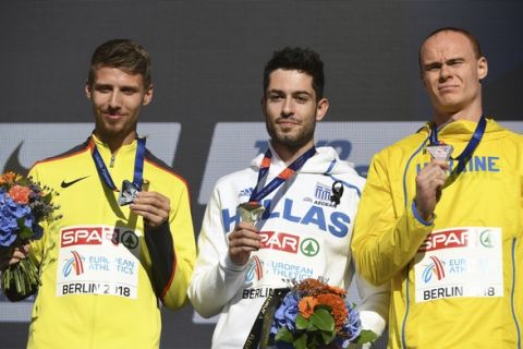 Greece's gold medal winner Miltiadis Tentoglou is flanked by Germany's silver medal winner Fabian Heinle, left, and Ukraine's bronze medal winner Serhii Nykyforov during the ceremony for the men's long jump at the European Athletics Championships in Berlin Friday, Aug. 10, 2018. (Hendrik Schmidt/dpa via AP)