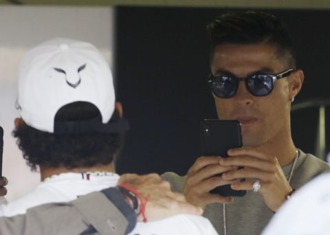 Cristiano Ronaldo, right, takes pictures to Mercedes driver Lewis Hamilton of Britain at the pit line ahead of the second practice session at the Monaco racetrack, in Monaco, Thursday, May 23, 2019. The Formula one race will be held on Sunday. (AP Photo/Luca Bruno)