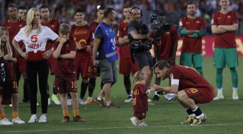 Roma's Francesco Totti kneels to look her younger daughter Isabel as he is saluting his fans after an Italian Serie A soccer match between Roma and Genoa at the Olympic stadium in Rome, Sunday, May 28, 2017. Francesco Totti played his final match with Roma against Genoa after a 25-season career with his hometown club. (AP Photo/Alessandra Tarantino) an Italian Serie A soccer match between Roma and Genoa at the Olympic stadium in Rome, Sunday, May 28, 2017. Francesco Totti is playing his final match with Roma against Genoa after a 25-season career with his hometown club. (AP Photo/Alessandra Tarantino)