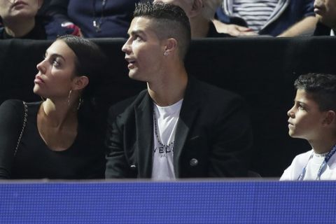 Cristiano Ronaldo, center, with his partner Georgina Rodriguez, and his son Cristiano Ronaldo Jr watch a screen as Novak Djokovic of Serbia plays John Isner of the United States in their ATP World Tour Finals singles tennis match at the O2 Arena in London, Monday Nov. 12, 2018. (AP Photo/Tim Ireland)