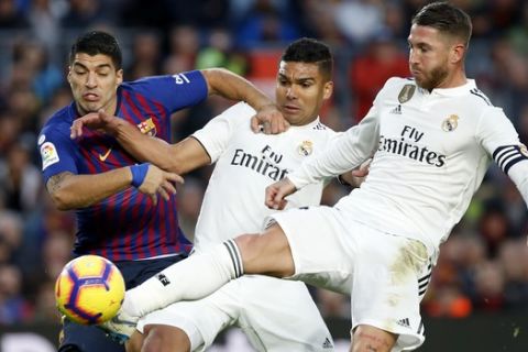 Barcelona forward Luis Suarez, left, duels for the ball with Real midfielder Casemiro, center, and Real defender Sergio Ramos during the Spanish La Liga soccer match between FC Barcelona and Real Madrid at the Camp Nou stadium in Barcelona, Spain, Sunday, Oct. 28, 2018. (AP Photo/Joan Monfort)
