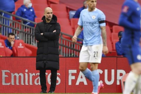 Manchester City's head coach Pep Guardiola, left, stands during the English FA Cup semifinal soccer match between Chelsea and Manchester City at Wembley Stadium in London, England, Saturday, April 17, 2021. (Ben Stansall, Pool via AP)