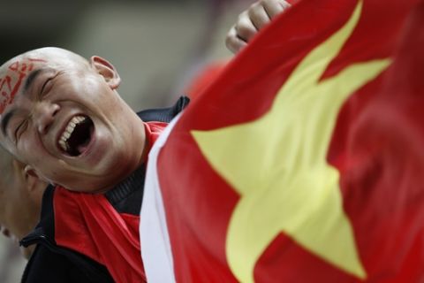 FILE - In this Wednesday, Jan. 12, 2011, file photo, a Chinese soccer fan cheers for his team before their AFC Asian Cup group A soccer match against Qatar in Doha, Qatar. Ever since the Chinese Football Association announced it had coaxed Lippi out of retirement, the nation's long-suffering fans have responded with more than a hint of skepticism. Given the team's record of failure under a string of foreign and Chinese coaches, the problems are more often attributed to the lack of a strong youth program and a misplaced, money-driven focus on the domestic league. (AP Photo/Hassan Ammar, File)