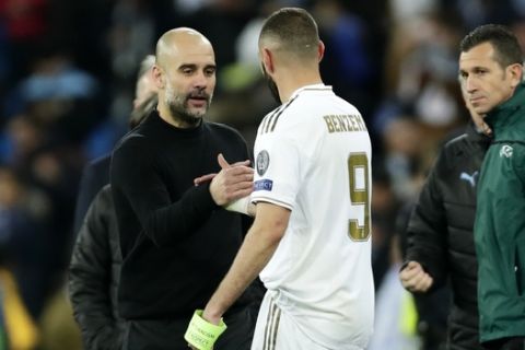 Manchester City's head coach Pep Guardiola, front left, shakes hands with Real Madrid's Karim Benzema at the end of the Champions League, round of 16, first leg soccer match between Real Madrid and Manchester City at the Santiago Bernabeu stadium in Madrid, Spain, Wednesday, Feb. 26, 2020. (AP Photo/Manu Fernandez)