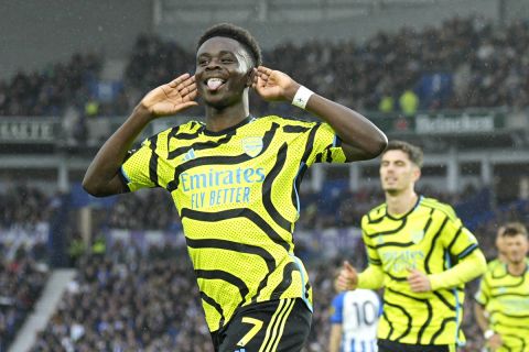 Arsenal's Bukayo Saka celebrates after scoring his side's opening goal during the English Premier League soccer match between Brighton and Hove Albion and Arsenal at the American Express Community Stadium in Brighton, England, Saturday, April 6, 2024. (AP Photo/Dave Shopland)
