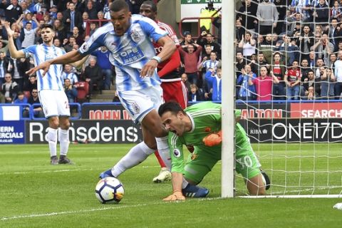 Huddersfield Town's Collin Quaner, center, has an attempt on goal stopped by Watford's goalkeeper Orestis Karnezis during their English Premier League soccer match at the John Smith's Stadium, Huddersfield, England, Saturday, April 14, 2018. (Dave Howarth/PA via AP)
