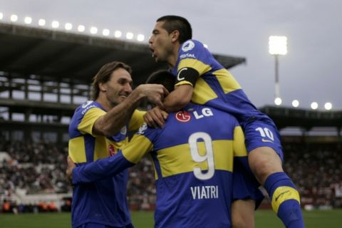 Boca Juniors' Lucas Viatri (9) is embraced by teammates Juan Roman Riquelme (R) and Rolando Schiavi after he scored a goal against Lanus during their Argentine First Division soccer match in Buenos Aires, September 18, 2011. REUTERS/Martin Acosta (ARGENTINA - Tags: SPORT SOCCER)