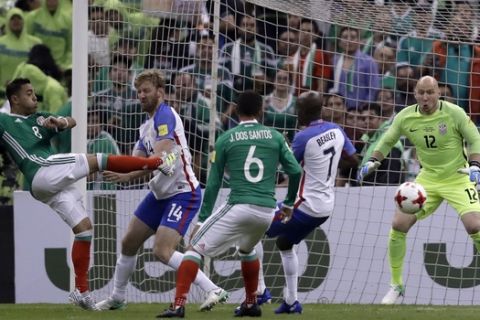 FILE - In this June 11, 2017, file photo, United States goalkeeper Brad Guzan, right, eyes the ball after Mexico's Marco De la Mora, left, shot trying to score during their World Cup soccer qualifying match in Mexico City. Midfielder Michael Bradley and goalkeeper Brad Guzan will be back with the U.S. national team for the first time since the loss at Trinidad and Tobago last October that ended the Americans' streak of seven straight World Cup appearances. (AP Photo/Rebecca Blackwell, File)