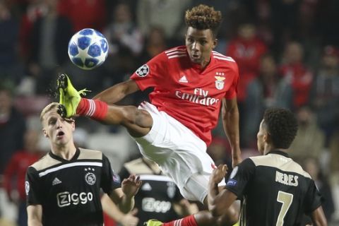 Benfica's Gedson Fernandes, center, jumps to kick the ball as Ajax's Donny van de Beek, left, and Ajax's David Neres, right, watch during the Champions League group E soccer match between Benfica and Ajax at the Luz stadium in Lisbon, Wednesday, Nov. 7, 2018. (AP Photo/Armando Franca)