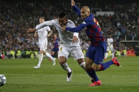 Barcelona's Martin Braithwaite, right, tries to get past Real Madrid's Casemiro during the Spanish La Liga soccer match between Real Madrid and Barcelona at the Santiago Bernabeu stadium in Madrid, Spain, Sunday, March 1, 2020. (AP Photo/Andrea Comas)