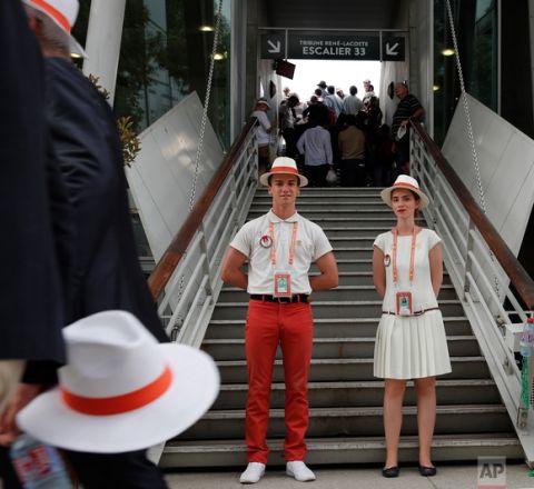 A hostess and host wait to welcome spectators at the Roland Garros stadium where the French Open tennis tournament is taking place in Paris, France. Friday, June 2, 2017. (AP Photo/Christophe Ena)