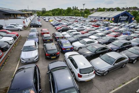 A used car sales garage forecourt holds loads of stock behind locked gates, in Bristol, England, Tuesday May 5, 2020.  The car market has suffered its "worst performance in living memory" according to trade figures released Tuesday with sales of new and used cars drastically impacted because of the COVID-19 coronavirus pandemic. (Ben Birchall/PA via AP)
