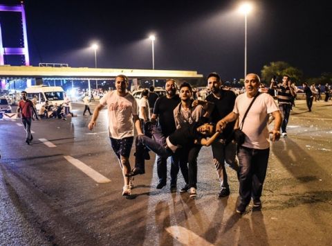 People carry a man shot during clashes with Turkish military at the entrance to the Bosphorus bridge in Istanbul on July 16, 2016. 
Turkish military forces on July 16 opened fire on crowds gathered in Istanbul following a coup attempt, causing casualties, an AFP photographer said. The soldiers opened fire on grounds around the first bridge across the Bosphorus dividing Europe and Asia, said the photographer, who saw wounded people being taken to ambulances.

 / AFP / Bulent KILIC        (Photo credit should read BULENT KILIC/AFP/Getty Images)