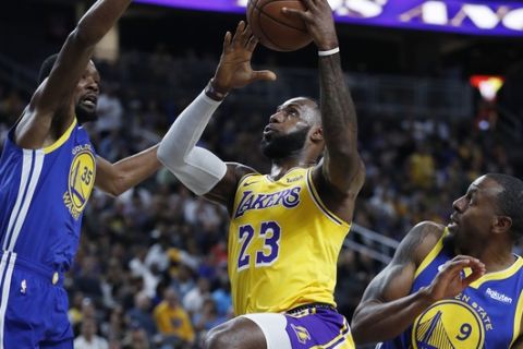 Los Angeles Lakers forward LeBron James (23) shoots between Golden State Warriors forward Kevin Durant, left, and guard Andre Iguodala during the first half of an NBA preseason basketball game Wednesday, Oct. 10, 2018, in Las Vegas. (AP Photo/John Locher)