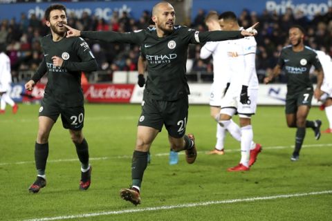 Manchester City's David Silva, centre, scores his side's first goal of the game against Swansea City, during their English Premier League soccer match at the Liberty Stadium in Swansea, England, Wednesday Dec. 13, 2017. (Nick Potts/PA via AP)