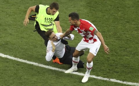 Croatia's Dejan Lovren and a steward grab a man who invaded the pitch during the final match between France and Croatia at the 2018 soccer World Cup in the Luzhniki Stadium in Moscow, Russia, Sunday, July 15, 2018. (AP Photo/Thanassis Stavrakis)