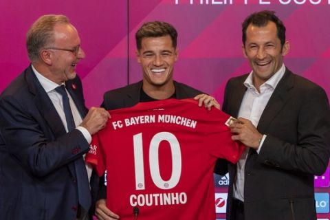 New player for Bayern Munich Philippe Coutinho, center, holds up a team shirt with his name on it with Karl-Heinz Rummenigge, left,  and coach Hasan Salihamidzic during a presser in their stadium in Munich, Germany, Monday, Aug. 19, 2019. Coutinho comes as a loaner for one year from FC Barcelona. (Peter Kneffel/dpa via AP)