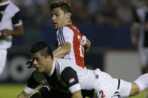 Lucas Boye of Argentina's River Plate, top, fights for the ball with Jorge Moreira of Paraguay's Libertad during a Copa Sudamericana soccer match in Asuncion, Paraguay, Thursday, Oct. 16, 2014. (AP Photo/Jorge Saenz)