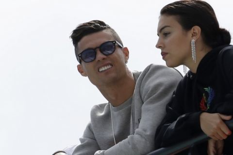 Cristiano Ronaldo, left, is flanked by his partner Georgina Rodriguez as they watch the second practice session at the Monaco racetrack, in Monaco, Thursday, May 23, 2019. The Formula one race will be held on Sunday. (AP Photo/Luca Bruno)
