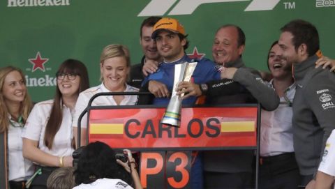 McLaren driver Carlos Sainz, of Spain, third from right, holds the third place trophy, accompanied at the podium by teammates, after the Brazilian Formula One Grand Prix at the Interlagos race track in Sao Paulo, Brazil, Sunday, Nov. 17, 2019. Sainz rose to the third position after Mercedes driver Lewis Hamilton, of Britain, received a post-race five-second punishment that demoted him to seventh place. (AP Photo/Silvia Izquierdo)