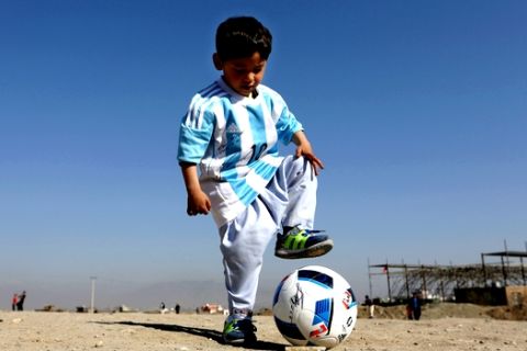 FILE - In this Friday, Feb. 26, 2016 file photo, Murtaza Ahmadi, a five-year-old Afghan Lionel Messi fan plays with a soccer ball during a photo opportunity as he wears a shirt signed by Messi, in Kabul, Afghanistan. The father of Ahmadi says the family was forced to leave Afghanistan amid constant telephone threats. (AP Photo/Rahmat Gul, File)