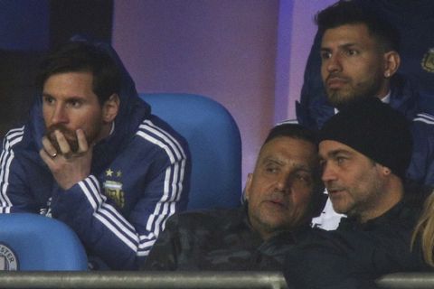 Argentina's Lionel Messi, left, and Sergio Aguero, top right, sit on the bench before the international friendly soccer match between Argentina and Italy at the Etihad Stadium in Manchester, England, Friday, March 23, 2018. (AP Photo/Dave Thompson)